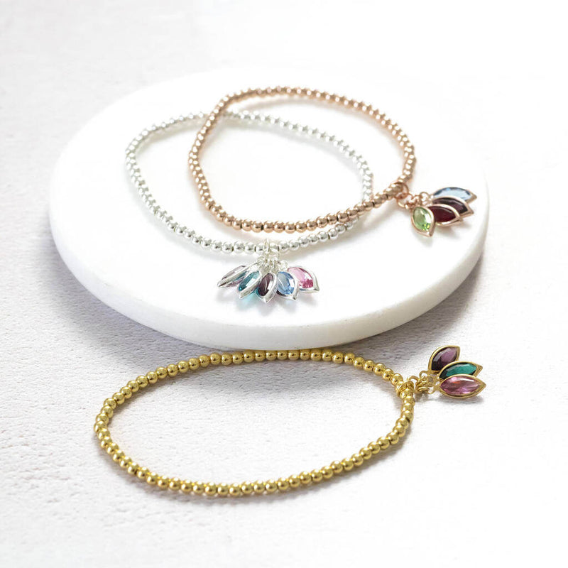 Image shows family marquise style birthstone bracelet from top to bottom: rose gold with August peridot, January Garnet, February Amethyst and March Aquamarine. Silver bracelet with June light amethyst, December blue zircon, February amethyst, March aquamarine and October rose swarovski birthstones. Gold plated bracelet with october rose, may emerald and february amethyst birthstones. 