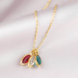 mages shows gold family marquise style birthstone necklace with Swarovski birthstones: January Garnet, April crystal and December blue zircon on a plain backdrop
