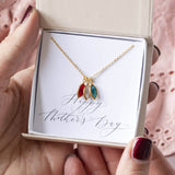 Images shows gold family marquise style birthstone necklace with Swarovski birthstones: January Garnet, April crystal and December blue zircon on a 'Happy Mother's Day' sentiment card inside the JOY branded gift box.