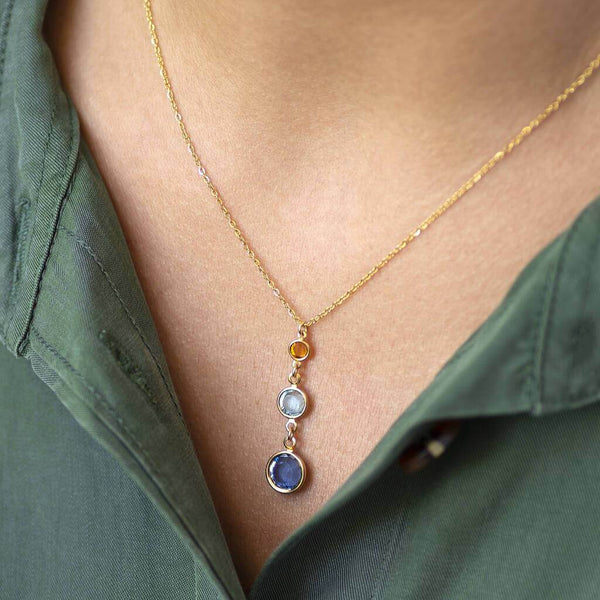 Model wears Gold Three Generations Birthstone Pendant Necklace. Swarovski birthstones arranged from bottom to top in selection order: September Sapphire, March Aquamarine and November Yellow Topaz.