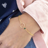 Model wears minimalist gold circle birthstone bracelet with May Emerald Swarovski Birthstone.