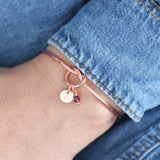 Model wears rose gold plated Friendship Knot Bangle with a small disc initial charm with the letter 'R' and a small amethyst Swarovski birthstone charm for the month of February.