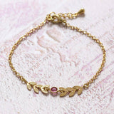 Image shows gold leaf vine bracelet with October rose birthstone detail.