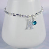 Image shows silver plated initial and charm bracelet displayed on a bracelet stand, with the initial 'A' and the December Blue Zircon Swarovski birthstone crystal.