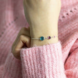 Model wears Sterling Silver Three Generations Birthstone Bracelet with the following birthstones from the left: December Blue Zircon, February Amethyst and October Rose.