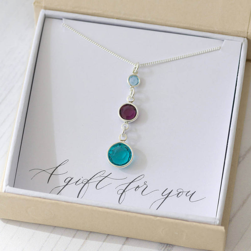 Image shows Sterling Silver Three Generations Birthstone Necklace with the following birthstones in selection order from bottom to top, December Blue Zircon, February Amethyst, March Aquamarine. Necklace is presented in a JOY gift box on the 'A Gift for You' sentiment card.