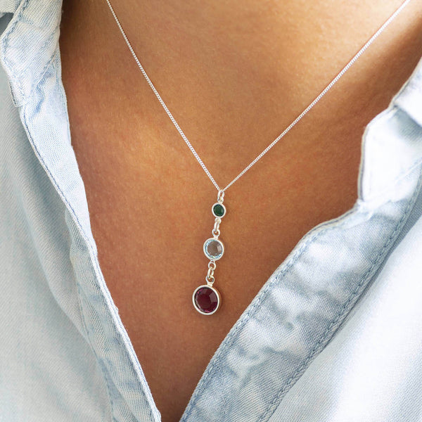 Model wears Sterling Silver Three Generations Birthstone Necklace. Birthstones from bottom to top (selection order) February Amethyst, March Aquamarine, May Emerald..