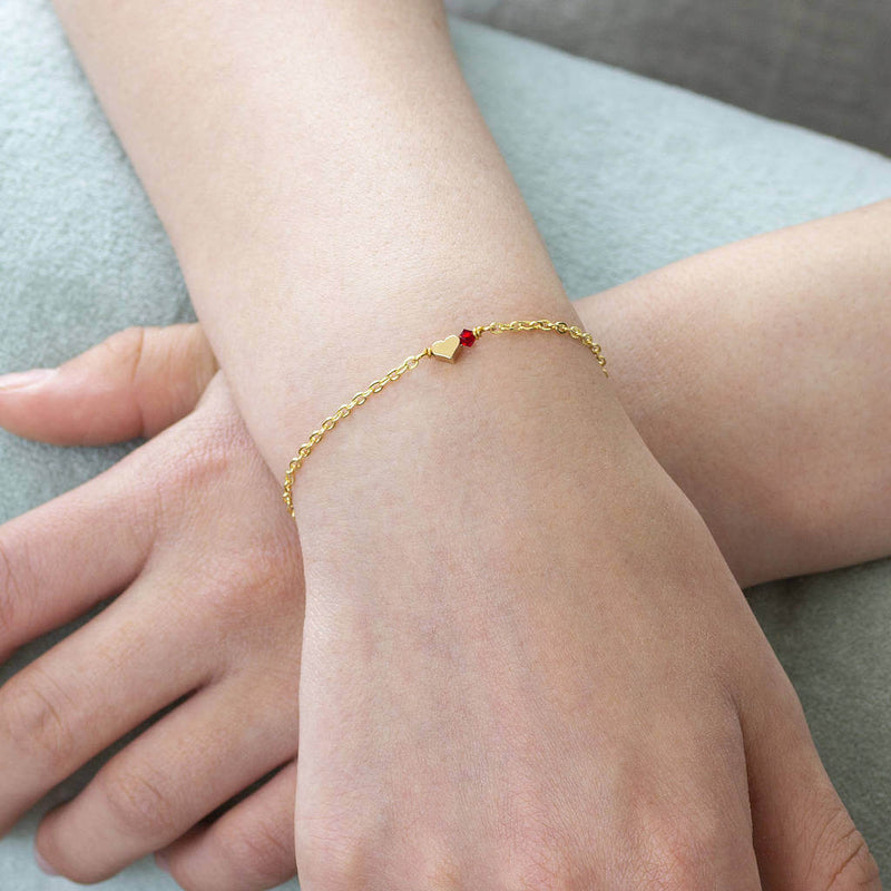Model wears tiny gold plated heart bracelet with January Garnet Swarovski Birthstone bead.