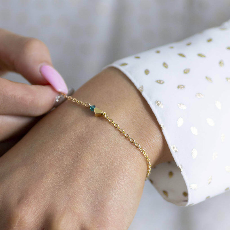 Model wears tiny gold plated heart bracelet with December Blue Zircon Swarovski Birthstone bead.