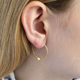 Model wears tiny gold plated heart hoop earrings in 4mm. 