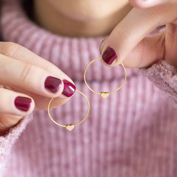 Model holds tiny gold plated heart hoop earrings in 4mm. 