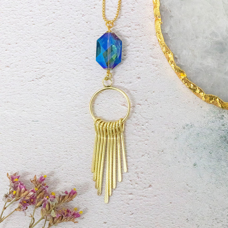 Image shows blue crystal astral necklace with gold embellishment on a white background.