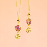 images shows two purple hex eclipse necklaces with full moon charms on a pink background.