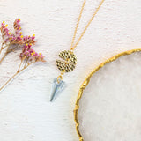 Image shows ero blue moon phase necklace on a white backdrop. Pendant features a blue swarovski crystal and two gold plated hammerend moon phases which when together makes a full moon.