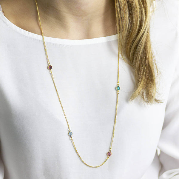Model wears gold plated long family birthstone necklace with four Swarovski birthstone crystals