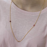 Model wears gold plated long family birthstone necklace with three Swarovski birthstone crystals