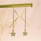 image shows a pair of interstellar gold plated dangle earrings complete with tiny crystal encrusted star.