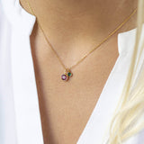 Model wears gold plated mother and child birthstone charm necklace with February purple amethyst and May emerald Swarovski crystal birthstones.