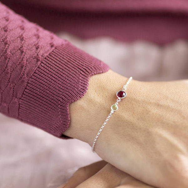 Model wears silver plated mother and daughter birthstone bracelet with August Peridot for daughter and July Ruby for mother.