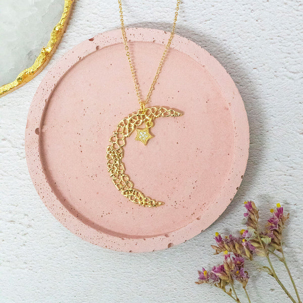Image shows a Nova crescent moon pendant necklace on a pink background
