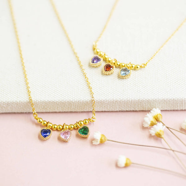 Image shows two Beaded Triple Birthstone Heart Necklaces with three birthstone hearts sitting on a white backdrop.