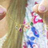 model holds up charm bracelet with family birthstone teardrop charms