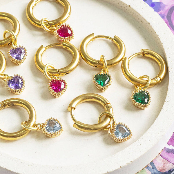 Gold huggie hoop earrings with heart birthstone charm detail