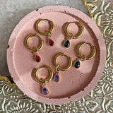 Image shows huggie hoop earrings with teardrop birthstone detail