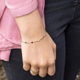 Model wears mini gold family birthstone bracelet with six mini Swarovski Birthstones (up to eight can be selected) Birthstones from left to right are; April Crystal, May Emerald, July Ruby, March Aquamarine, October Rose, August Peridot.