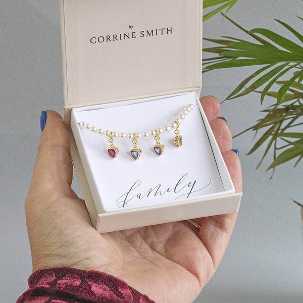 image shows pearl bracelet with family birthstone hearts on a 'family' sentiment card within a JOY by Corrine Smith gift box