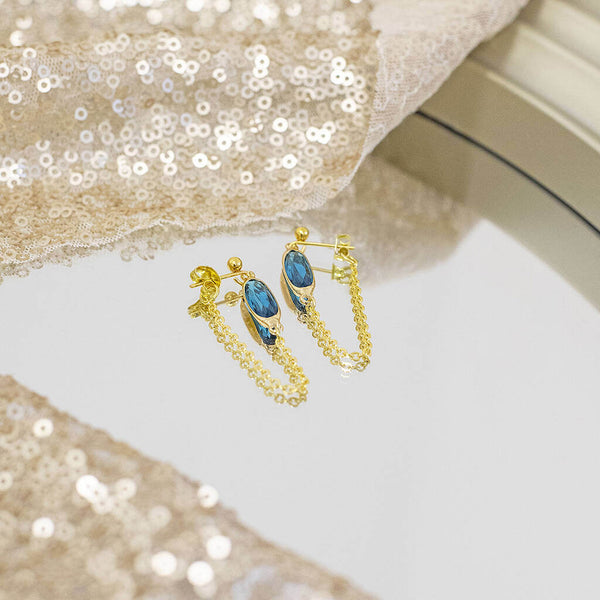 image shows gold pated oval birthstone chain drop earrings with december zircon birthstone.