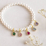 image shows pearl bracelet with family birthstone teardrops. Five birthstones appear here to represent different family members.