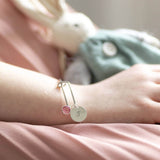 Model wears personalised birthstone christening bangle with Swarovski birthstone and hand stamped initial disc with the letter 'S'