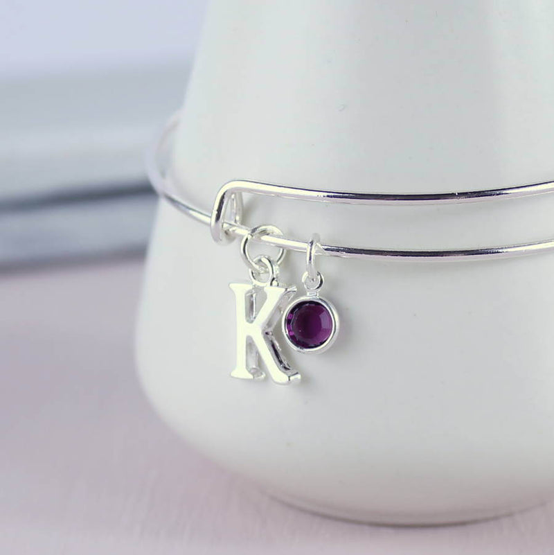 Image shows personalised initial birthstone bangle with initial 'K' and a Swarovski birthstone charm.