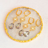 image shows two pairs of radiance sunburst earrings with grey crystal and sunburst charm on a white background.