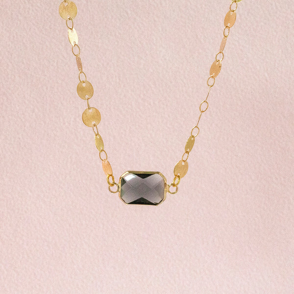 image shows sparkling satellite necklaces complete with dark grey crystal sitting on a pink backdrop.