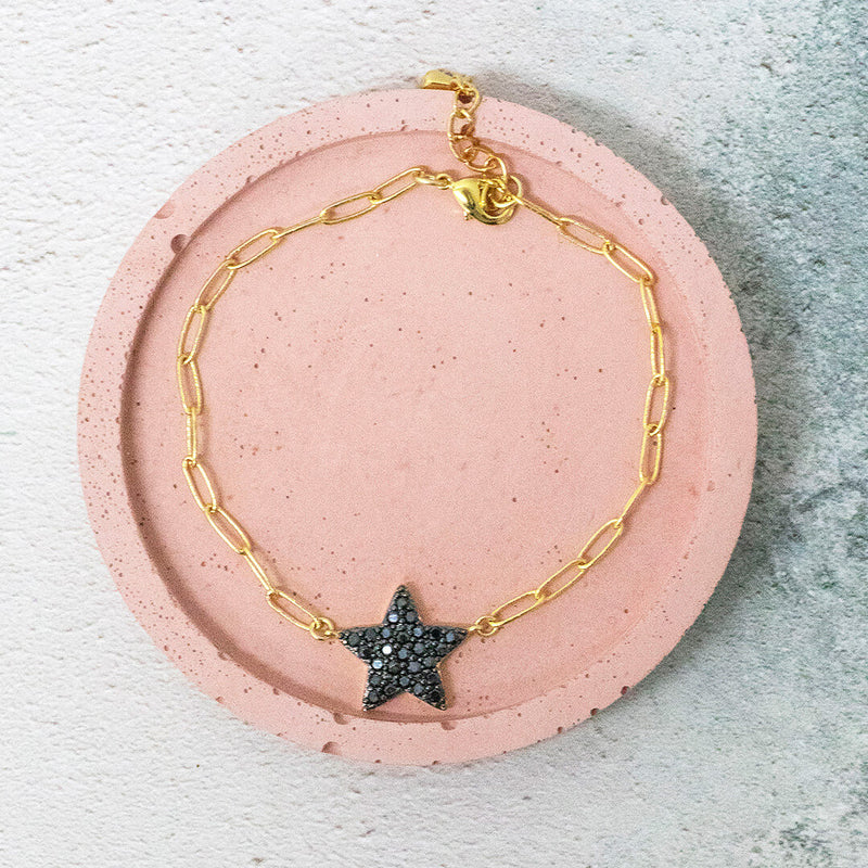 image shows sirius black bracelet on a pink backdrop. Bracelet has large links complete with a black crystal encrusted star.